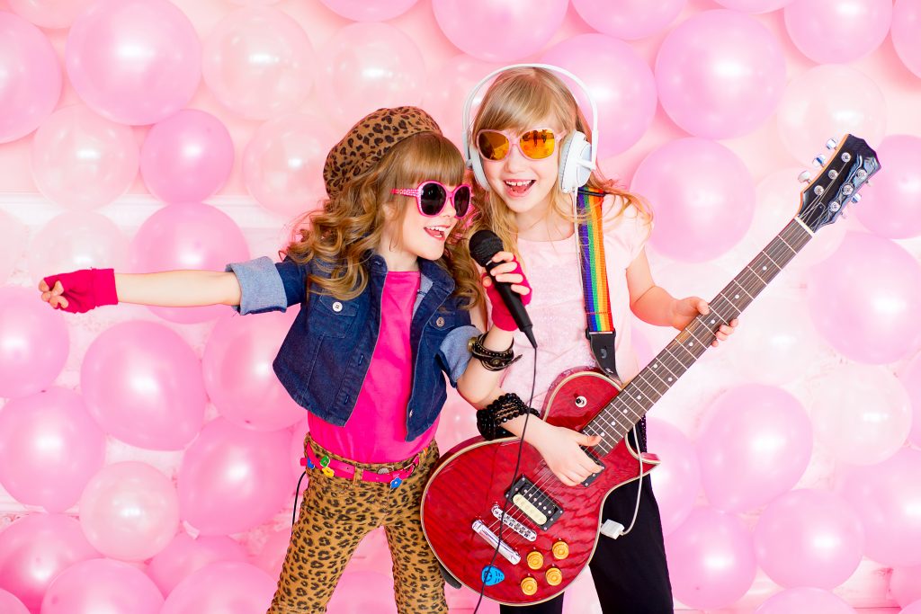 Niñas cantando con una guitarra y un micrófono